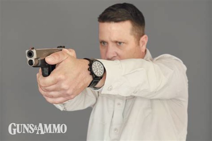 A man points a gun off-screen while four others look at him. 
